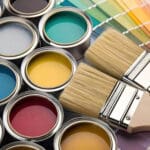 Best paint finishes for busy living areas shown with open paint cans, color swatches, and paint brushes laid out for interior painting projects