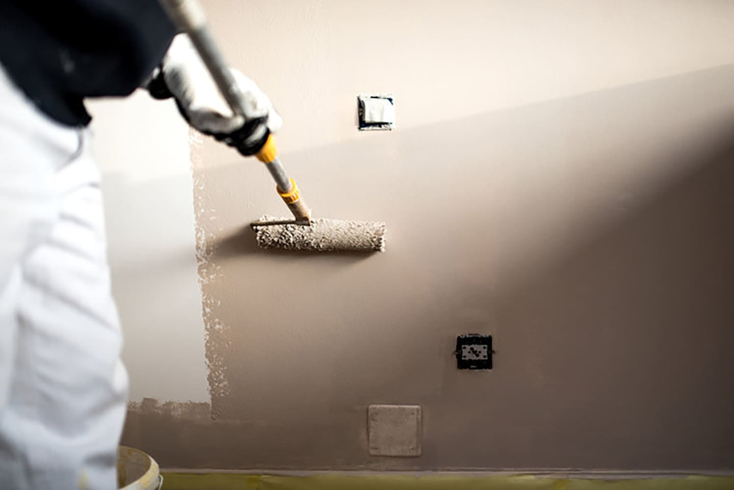 Professional painter applying fresh interior wall paint with a roller