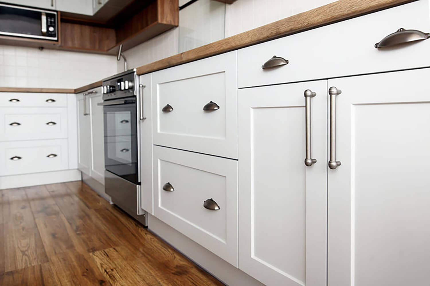 Freshly updated white kitchen cabinets showing when to refinish or replace kitchen cabinets based on cabinet condition, finish quality, and overall kitchen layout.