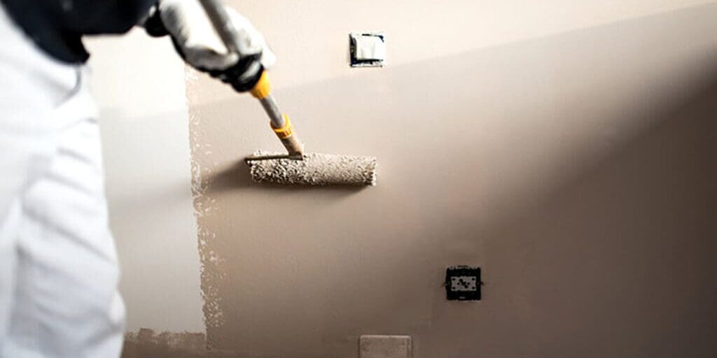 Professional painter applying fresh interior wall paint with a roller